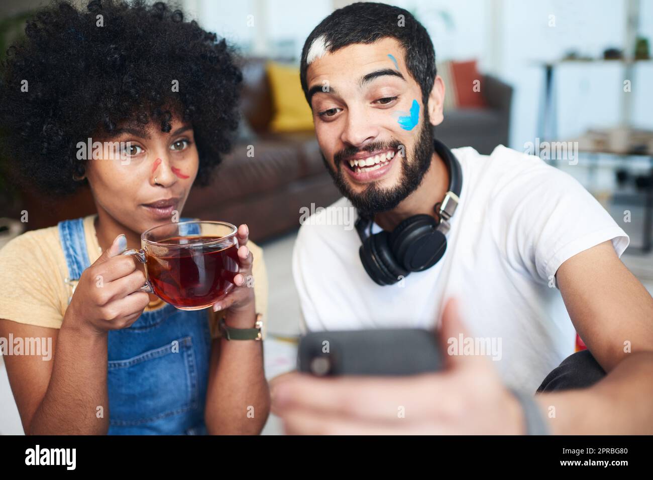 Nous avons fini par une belle peinture et des souvenirs encore meilleurs. Un homme tenant son téléphone portable tout en étant assis à la maison avec sa petite amie. Banque D'Images