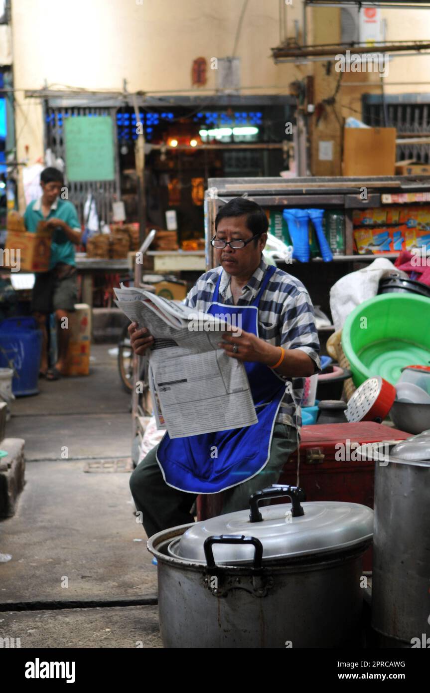 Un thaïlandais lisant le journal du matin sur un marché local à Bangkok, en Thaïlande. Banque D'Images