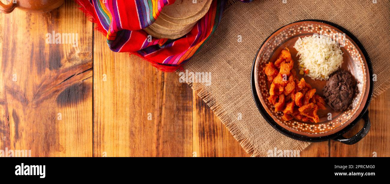 Rince-porc à la sauce rouge, accompagné de riz et de haricots réfrits. Plat traditionnel fait maison très populaire au Mexique, ce plat fait partie du popoul Banque D'Images