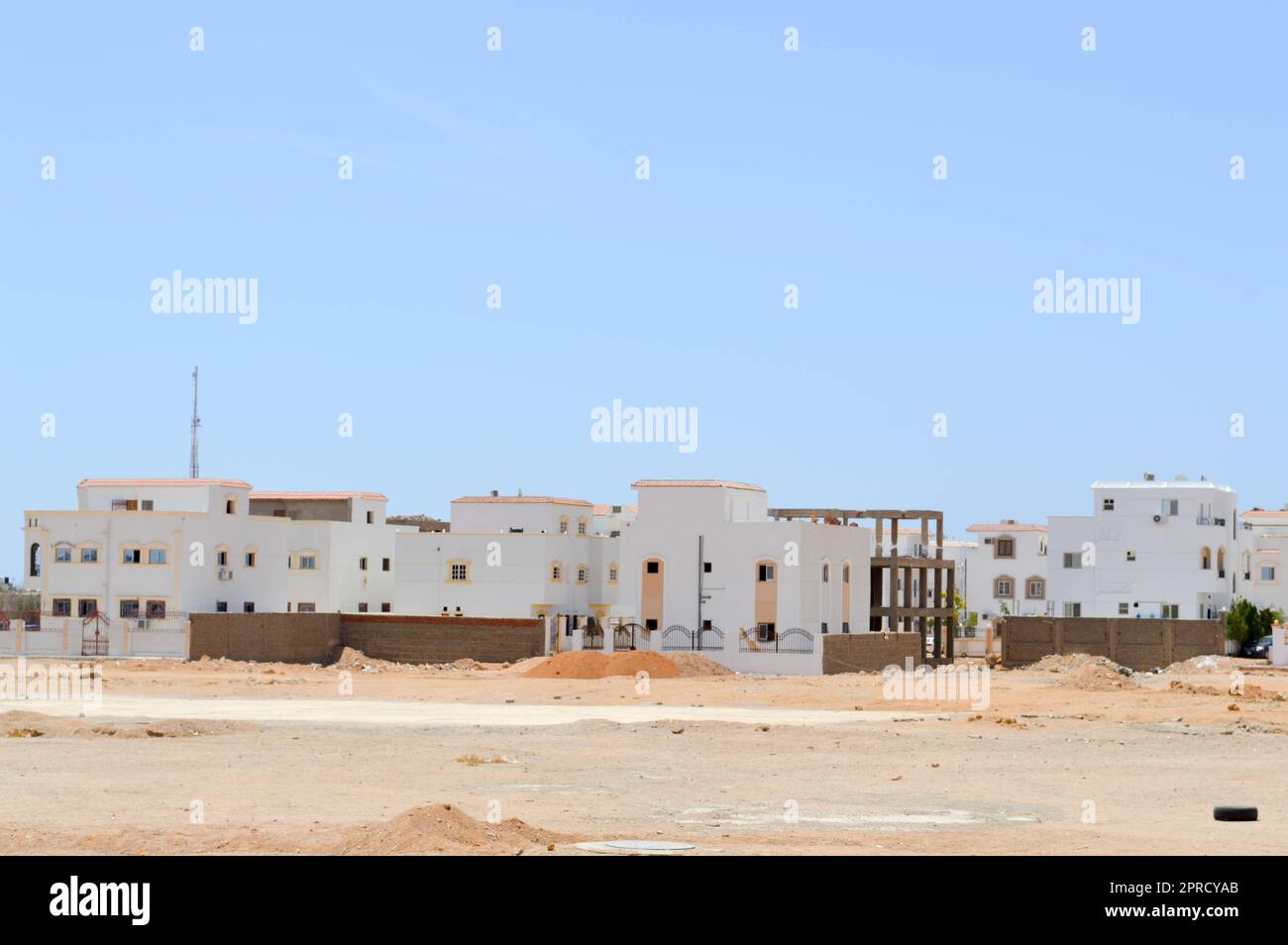 Maisons rectangulaires blanches arabes dans le désert avec des fenêtres sur fond de sable jaune et le ciel bleu. Banque D'Images