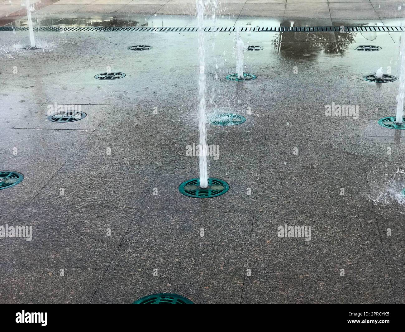 Une petite belle fontaine de chant en plein air, dans la rue. Gouttes d'eau, jets d'eau congelés dans l'air en vol sur le fond de Banque D'Images