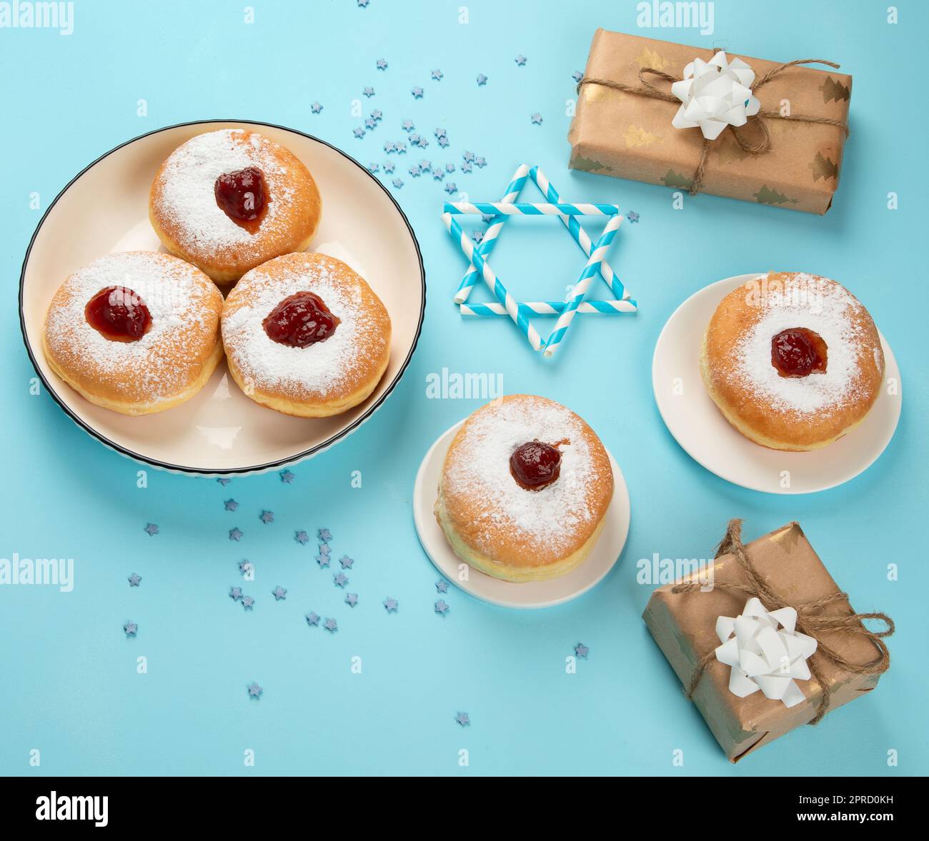 Sufganiyot (beignets traditionnels) avec confiture de fruits et bougies blanches sur fond de papier bleu. Vacances juives Hanoukkah conc Banque D'Images