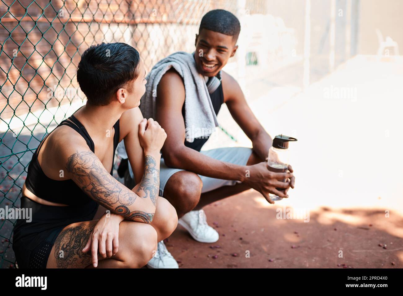 Deux jeunes sportifs bavardent les uns avec les autres contre une clôture en plein air. Banque D'Images