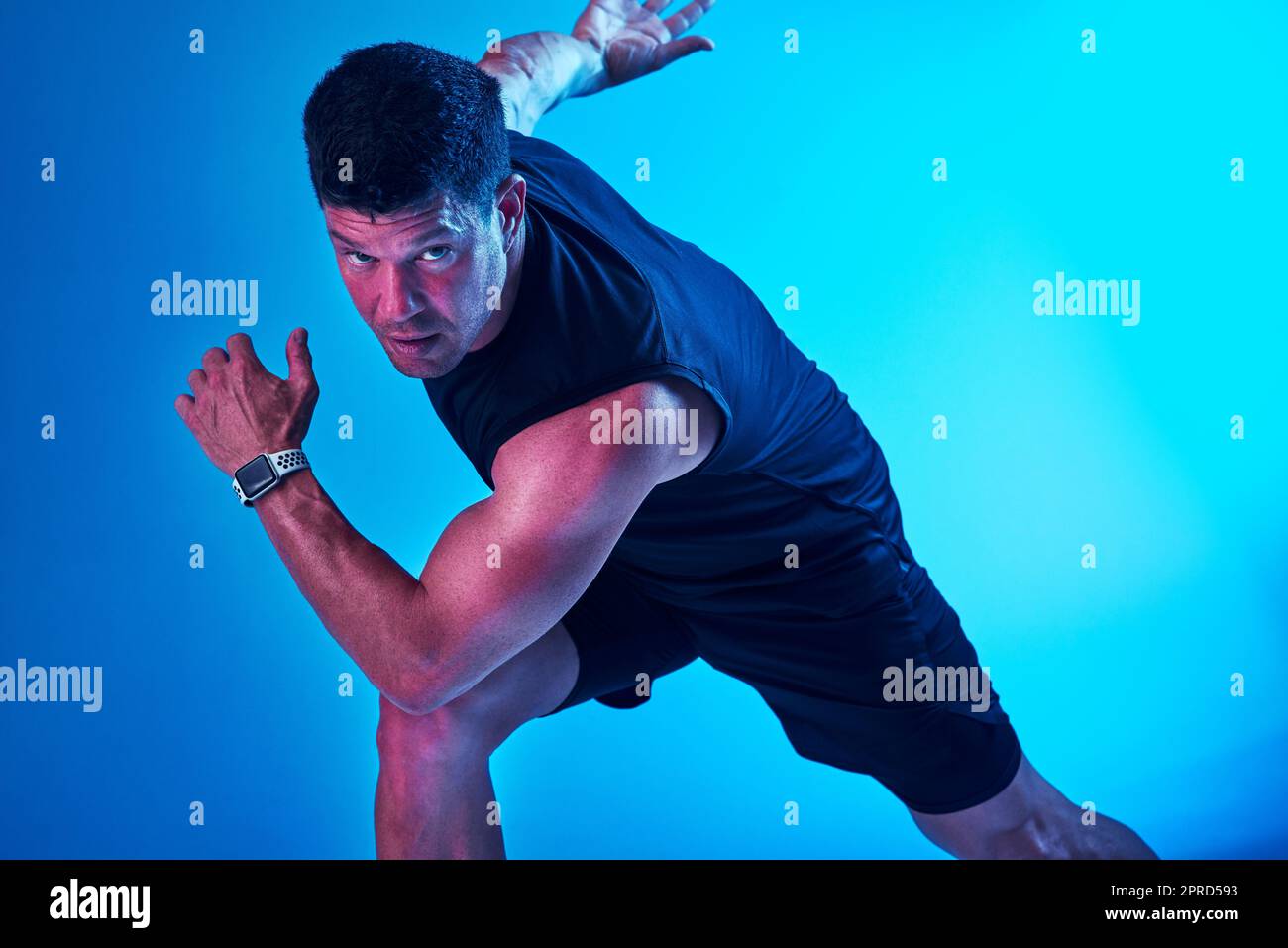 Prêt ou pas, ici je viens. Prise de vue filtrée bleue d'un sportif qui se pose en studio. Banque D'Images