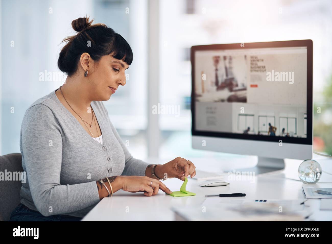 Il est essentiel de prendre des notes pour fixer des objectifs. Une jeune femme d'affaires attirante assise seule dans son bureau et utilisant des post-it pour prendre des notes. Banque D'Images