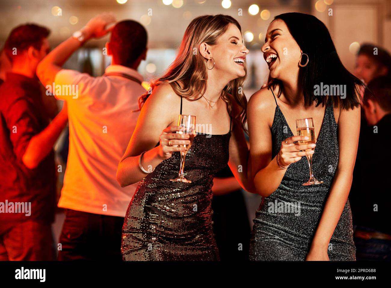 Nous devrions le faire plus souvent. Deux jeunes femmes gaies prenant des boissons tout en dansant sur la piste de danse d'une boîte de nuit. Banque D'Images