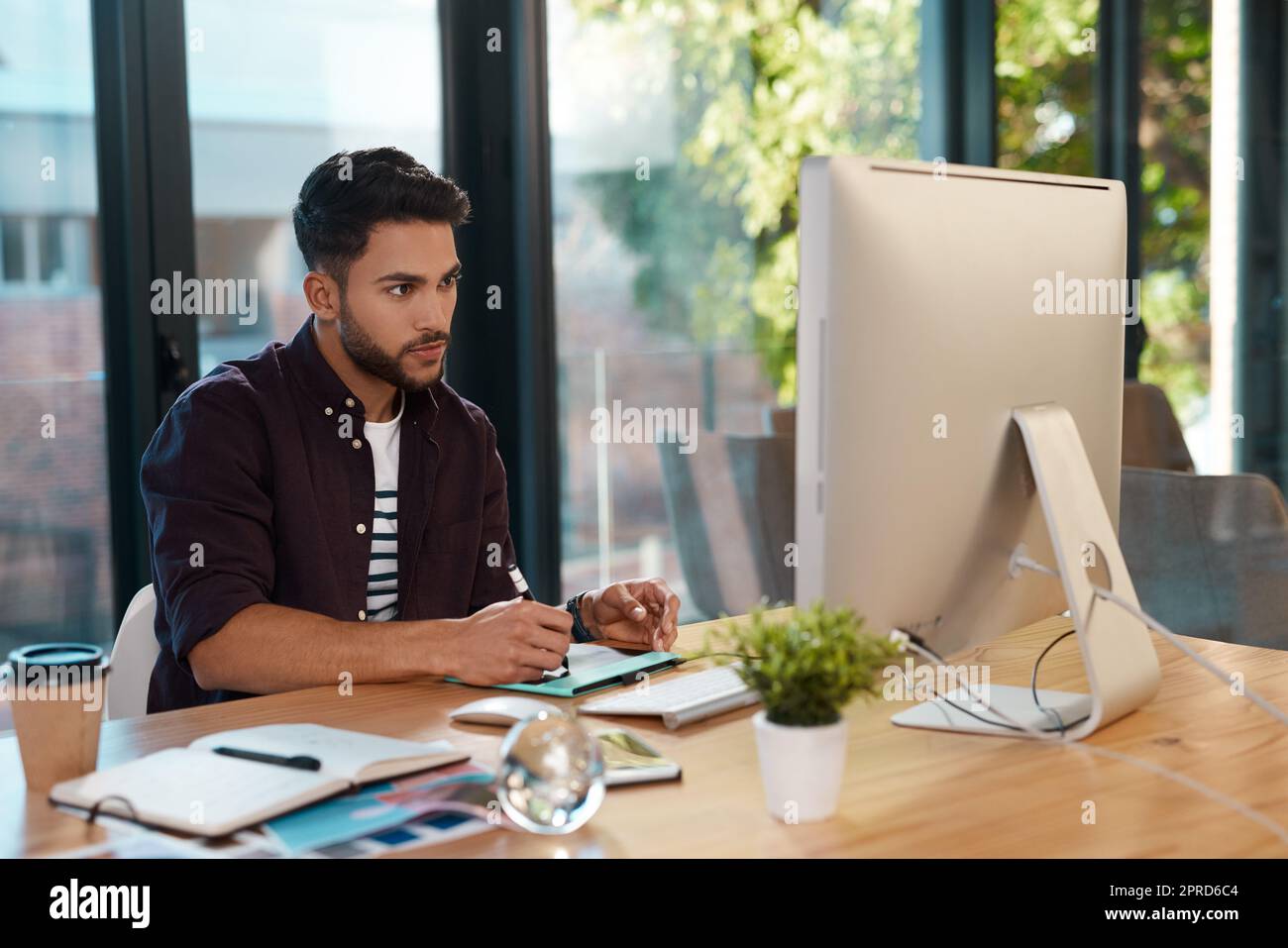 Je travaille sur mes compétences de montage. Un beau jeune homme d'affaires assis seul dans son bureau et de montage d'images. Banque D'Images