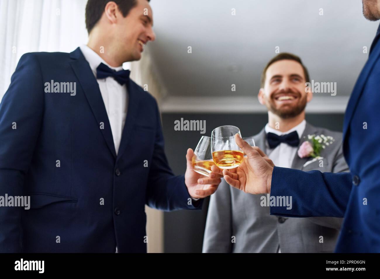 C'est votre dernier toast en tant qu'homme unique. Deux grooms non reconnaissables partageant un toast avec le marié le jour de son mariage. Banque D'Images