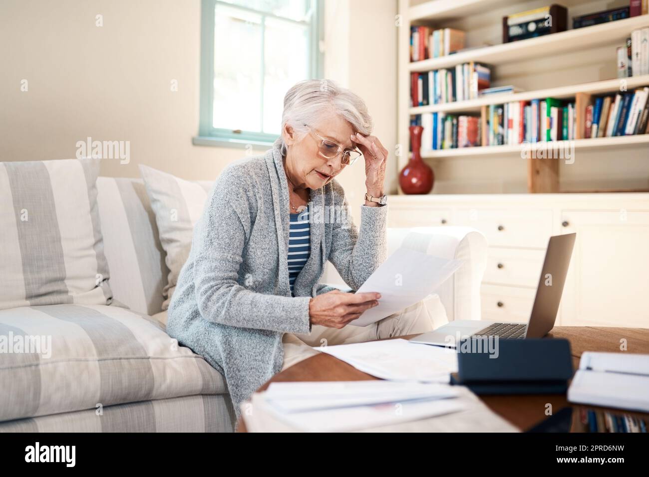 Comment vais-je le faire tout au long du mois. Une femme âgée qui regarde stressée tout en passant par la paperasse à la maison. Banque D'Images