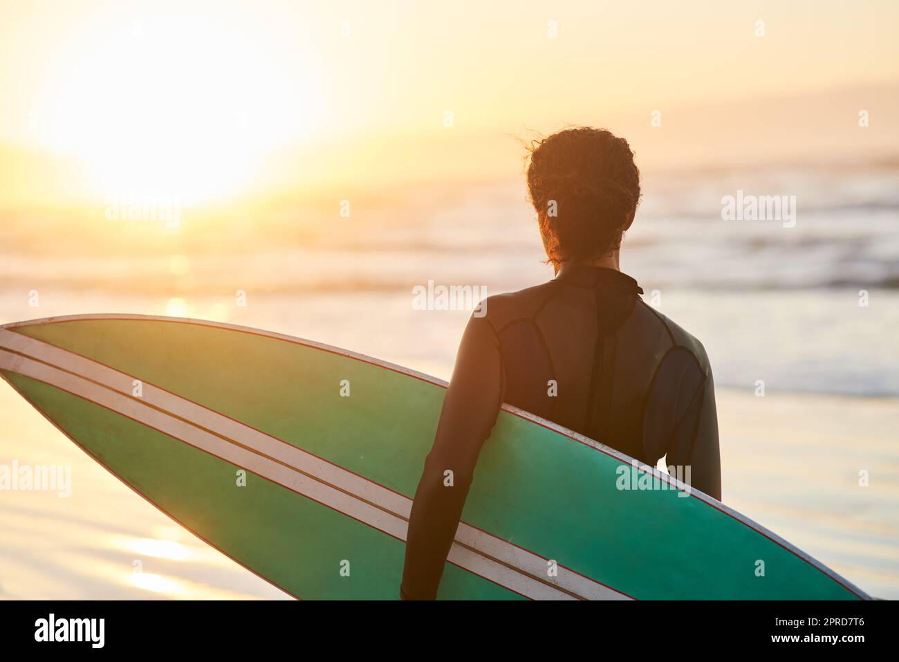 C'est aussi gratuit que l'océan. Vue arrière d'une femme portant sa planche de surf à la plage. Banque D'Images