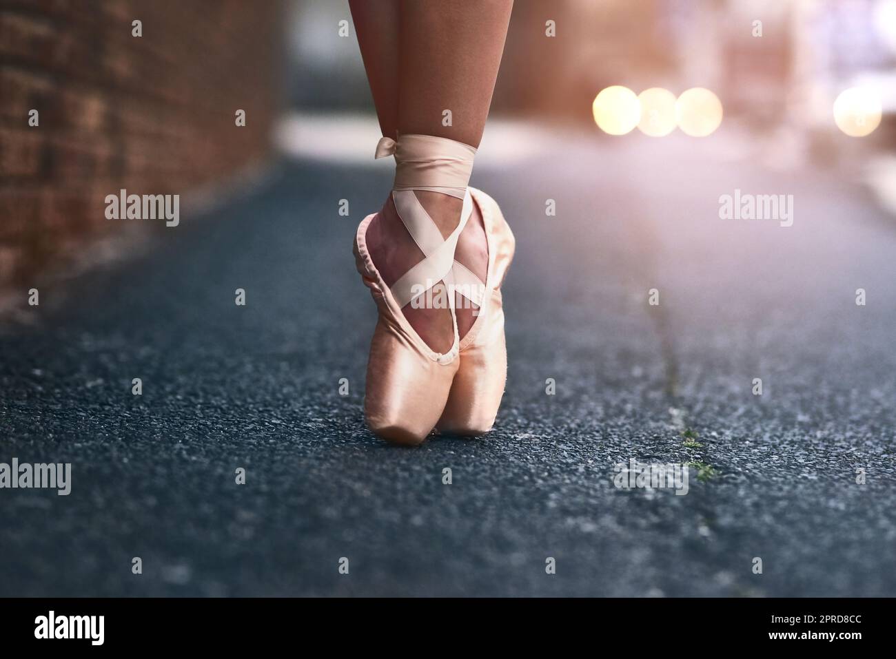 Le cœur d'une danseuse se trouve à ses pieds. Une danseuse de ballet debout sur des orteils contre un fond urbain. Banque D'Images