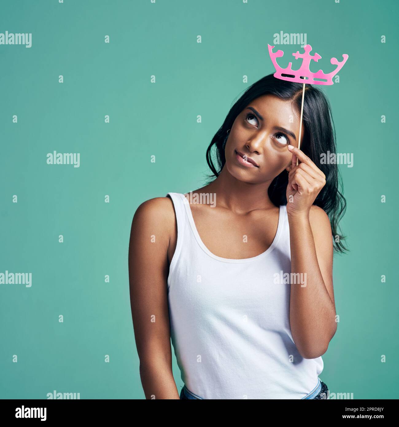 Pensées royales. Studio photo d'une belle jeune femme posant avec une couronne prop sur un fond vert. Banque D'Images