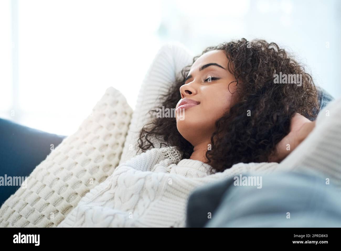 C'est un temps depuis que je me suis senti détendu. Une jeune femme assise sur le canapé à la maison avec ses yeux fermés. Banque D'Images
