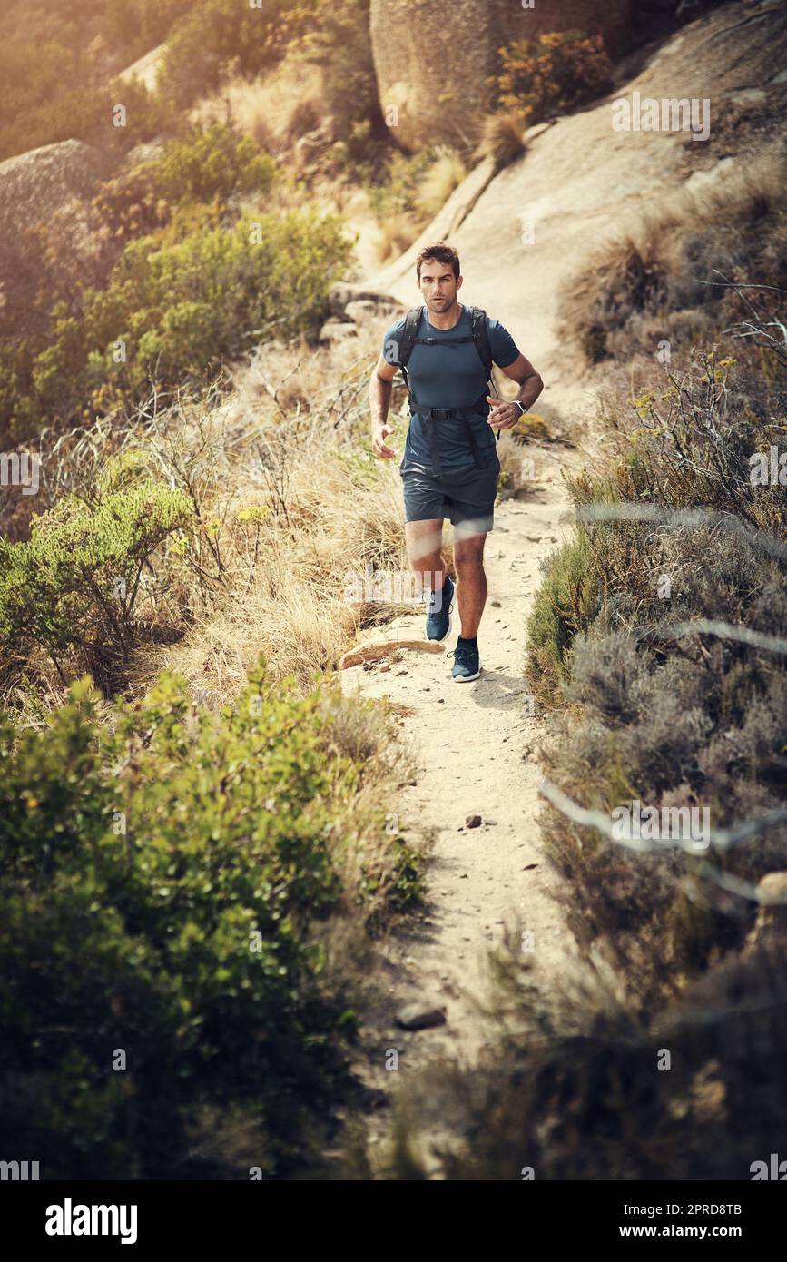 La randonnée pédestre est bonne pour le corps et l'esprit. Photo en longueur d'un beau jeune homme qui court pendant sa randonnée dans les montagnes. Banque D'Images