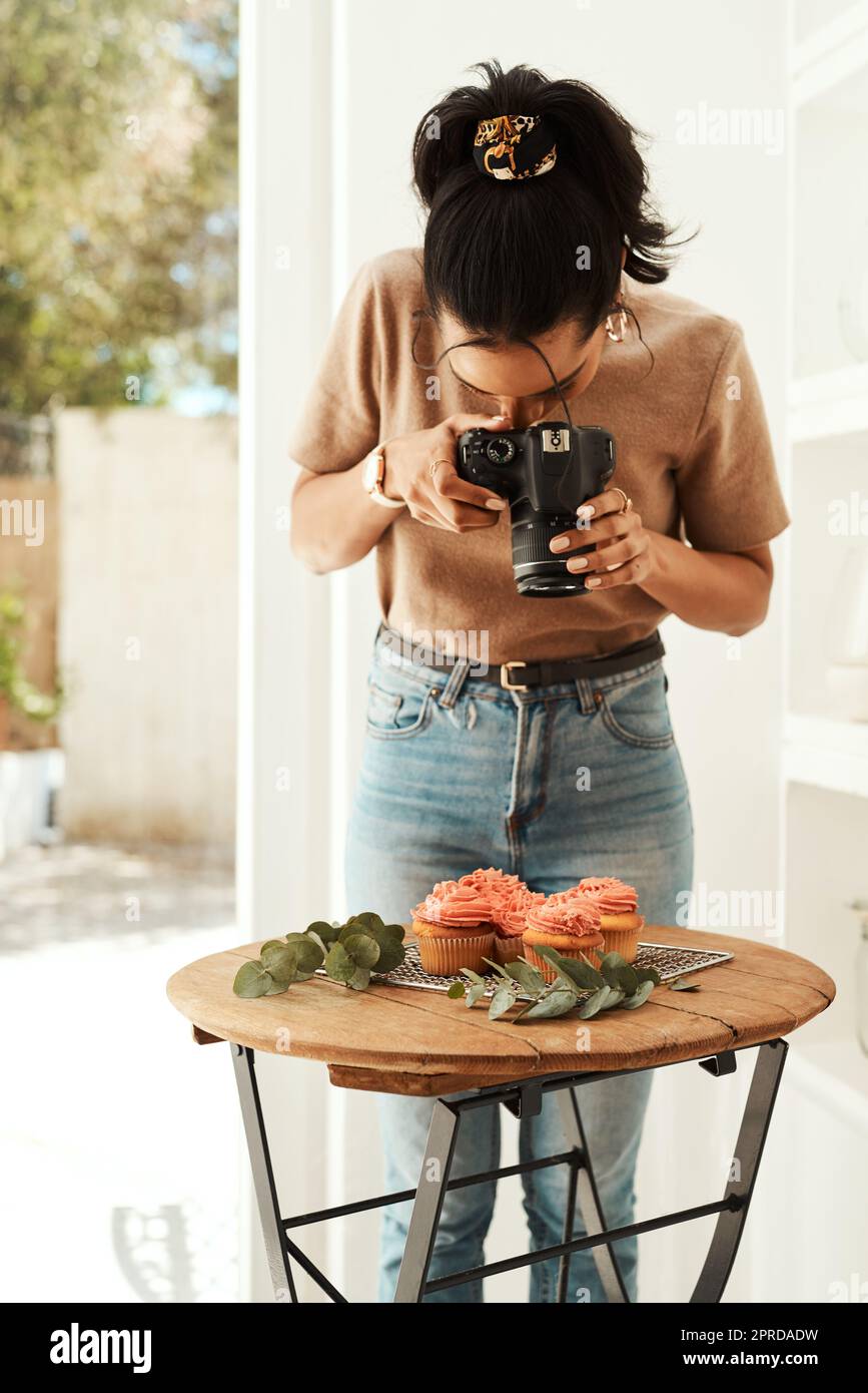 J'aime blogging. Une jeune femme d'affaires attrayante debout et utilisant son appareil photo pour photographier des cupcakes pour son blog. Banque D'Images