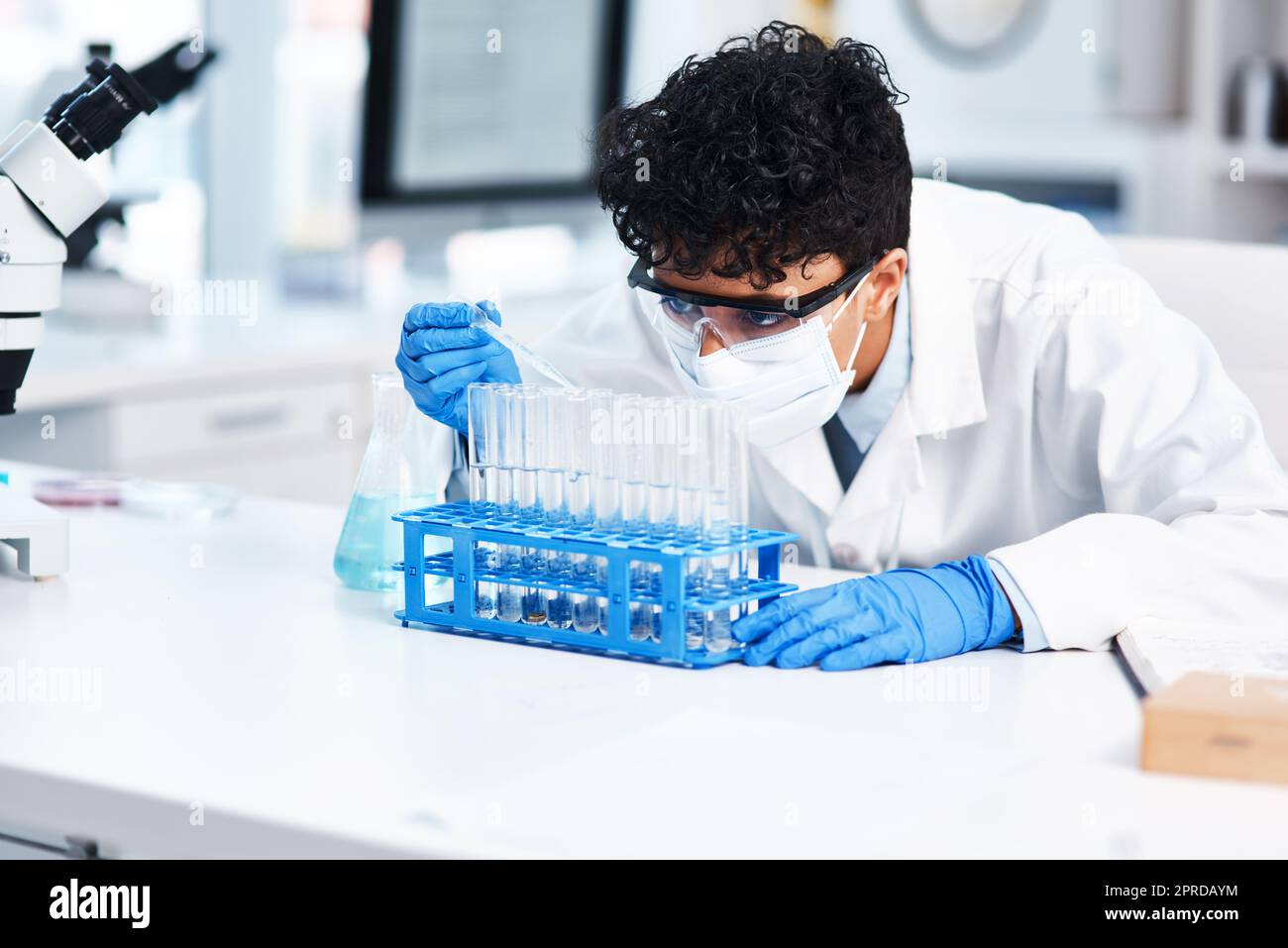 Cela se passe beaucoup dans ce laboratoire. Un jeune scientifique utilisant un compte-gouttes tout en travaillant avec des échantillons dans un laboratoire. Banque D'Images