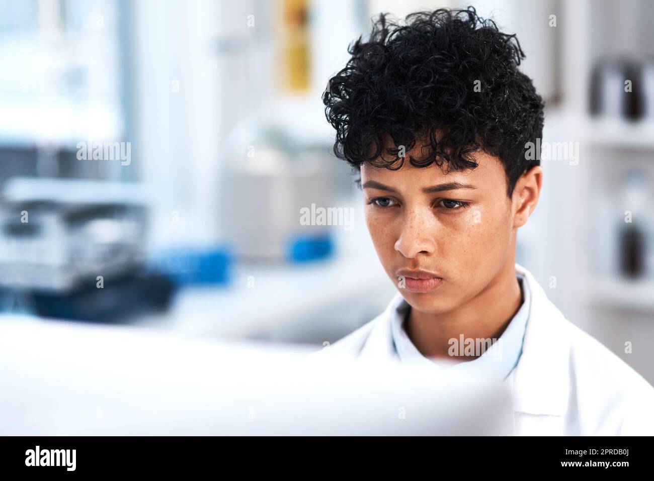 Son objectif ne faiblit jamais : un jeune scientifique travaillant sur un ordinateur dans un laboratoire. Banque D'Images