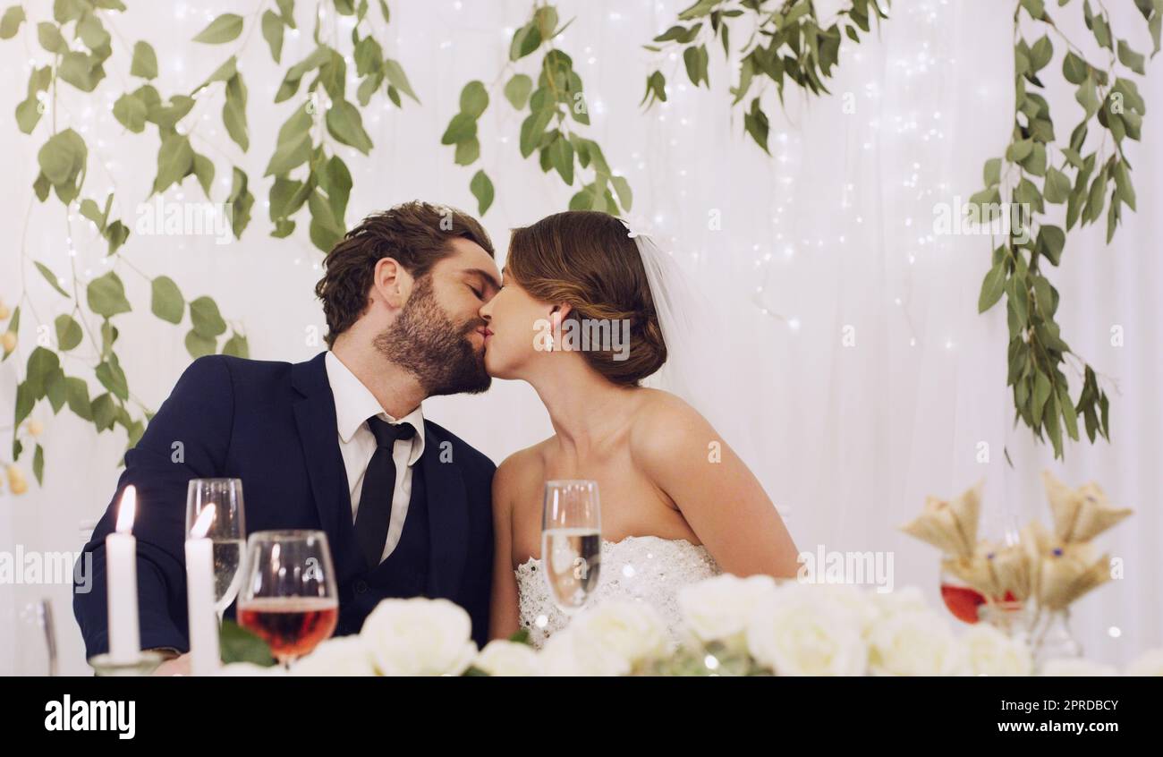 Lorsqu'ils s'embrassent, ils le font avec passion. Un jeune couple  affectueux qui s'embrasse tout en étant assis à leur réception de mariage  Photo Stock - Alamy