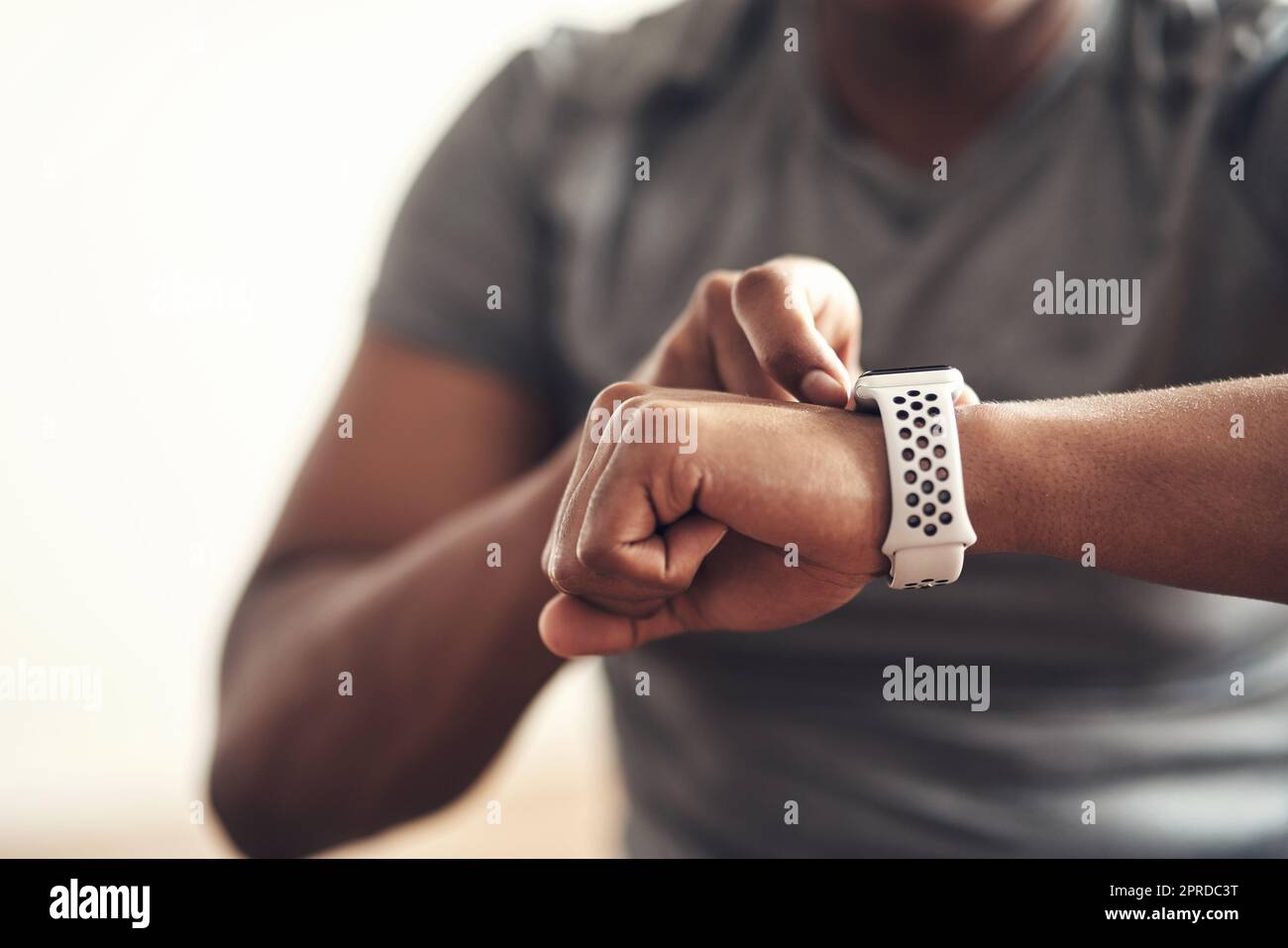 Ne vous laissez pas distancer, continuez à suivre le rythme. Gros plan d'un homme méconnaissable qui vérifie sa montre-bracelet tout en faisant de l'exercice à la maison. Banque D'Images