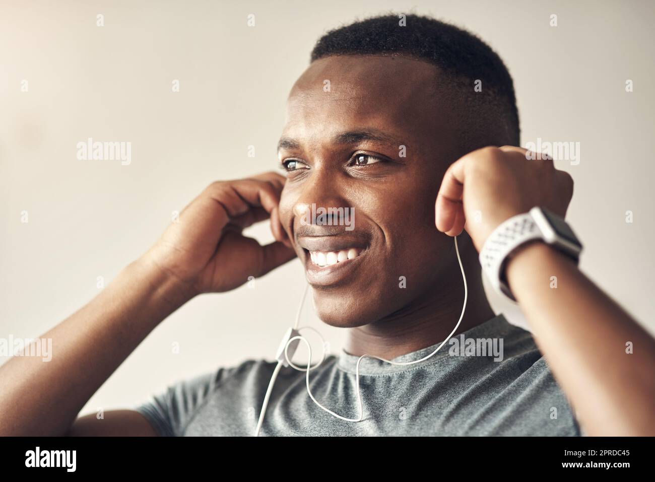 Il est temps de passer une autre journée de vibes saines. Un jeune sportif qui écoute de la musique tout en s'exerçant à la maison. Banque D'Images