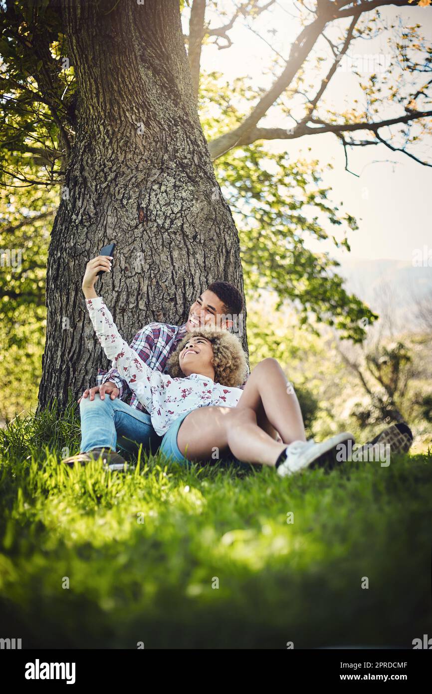 Nous faisons un couple si mignon. Un jeune couple prenant un selfie tout en passant la journée au parc. Banque D'Images