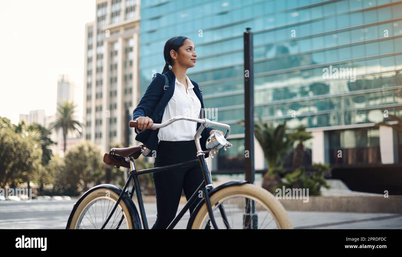 Ambition vous fait avancer. Une jeune femme d'affaires voyageant avec un vélo dans la ville. Banque D'Images