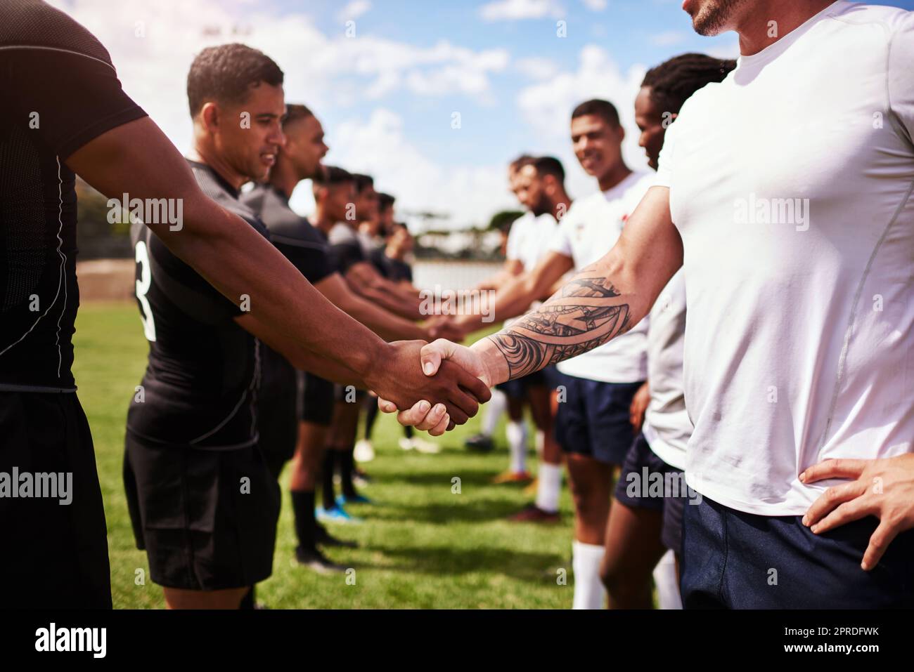 Jouez bien, jouez bien. Un groupe de jeunes joueurs de rugby se serrant la main sur le terrain. Banque D'Images