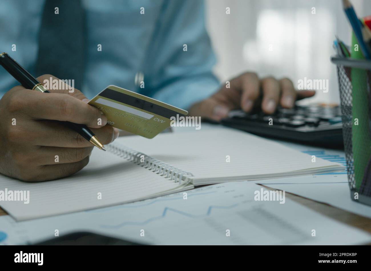 Homme tenant carte de crédit avec calculatrice paiement financement banque achat en ligne commerce concept d'affaires. Banque D'Images