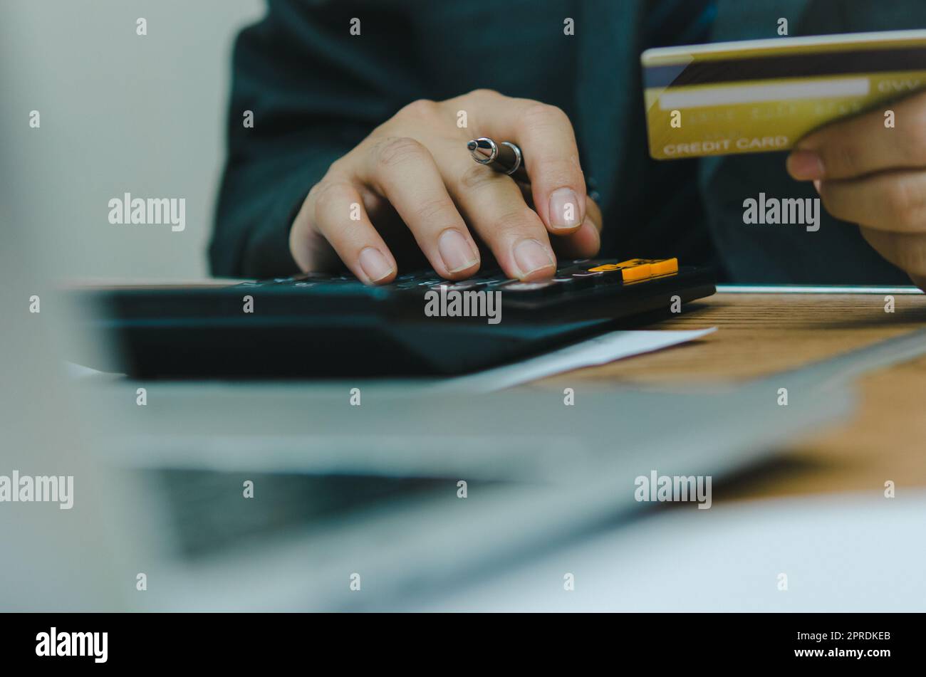 Homme tenant carte de crédit avec calculatrice paiement financement banque achat en ligne commerce concept d'affaires. Banque D'Images