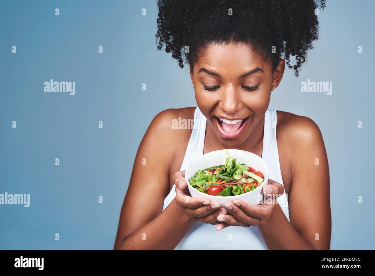 Il a l'air incroyable et le goût encore meilleur. Photo en studio d'une jeune femme attrayante qui mange de la salade sur fond gris. Banque D'Images