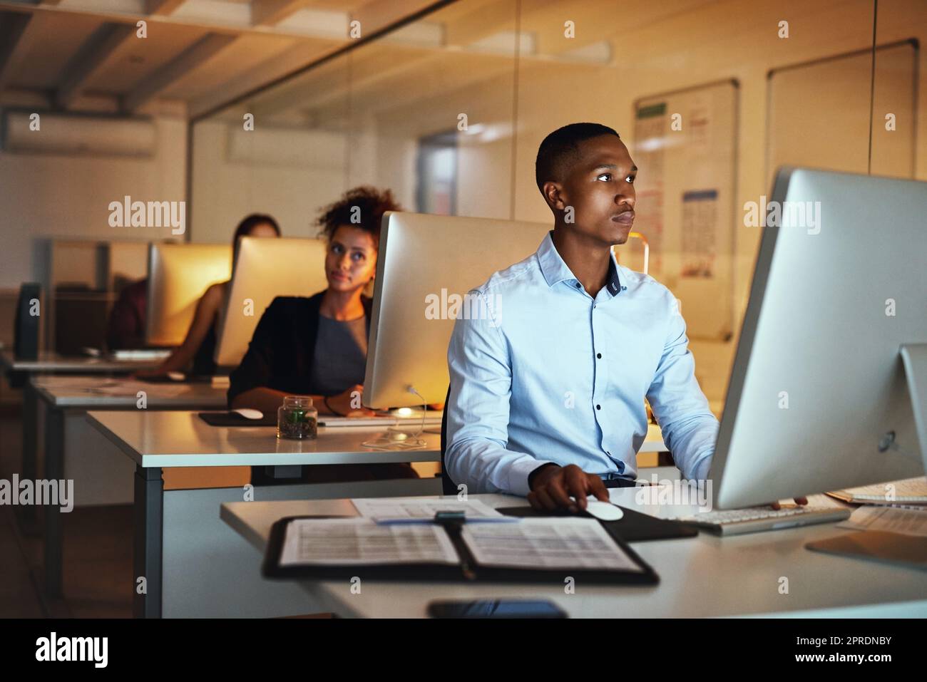 HES a eu l'engagement de faire le travail. Un jeune homme d'affaires travaillant tard sur un ordinateur dans un bureau. Banque D'Images