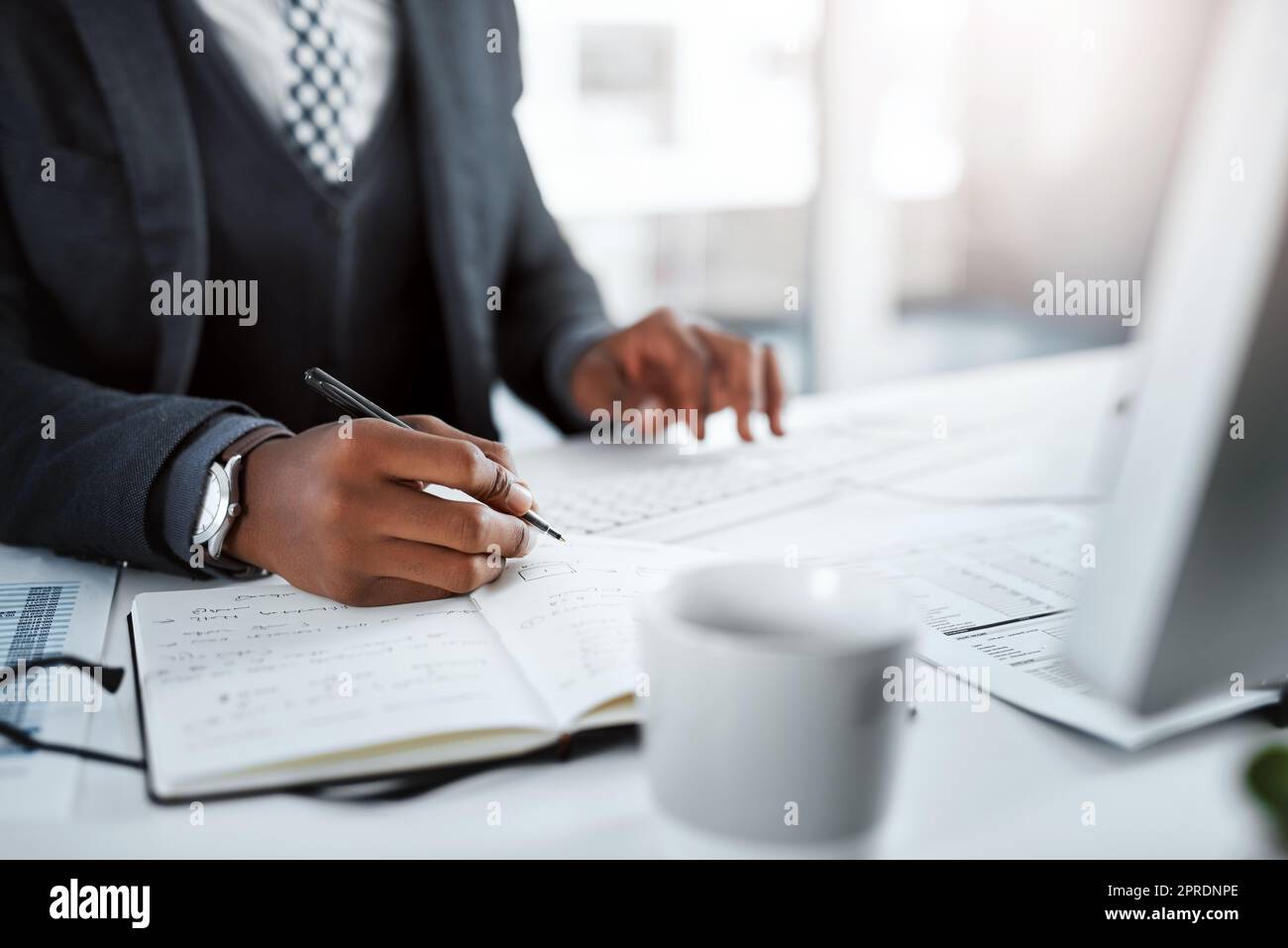 Le grand plan directeur. Un homme d'affaires utilisant un ordinateur et écrivant des notes à son bureau dans un bureau moderne. Banque D'Images