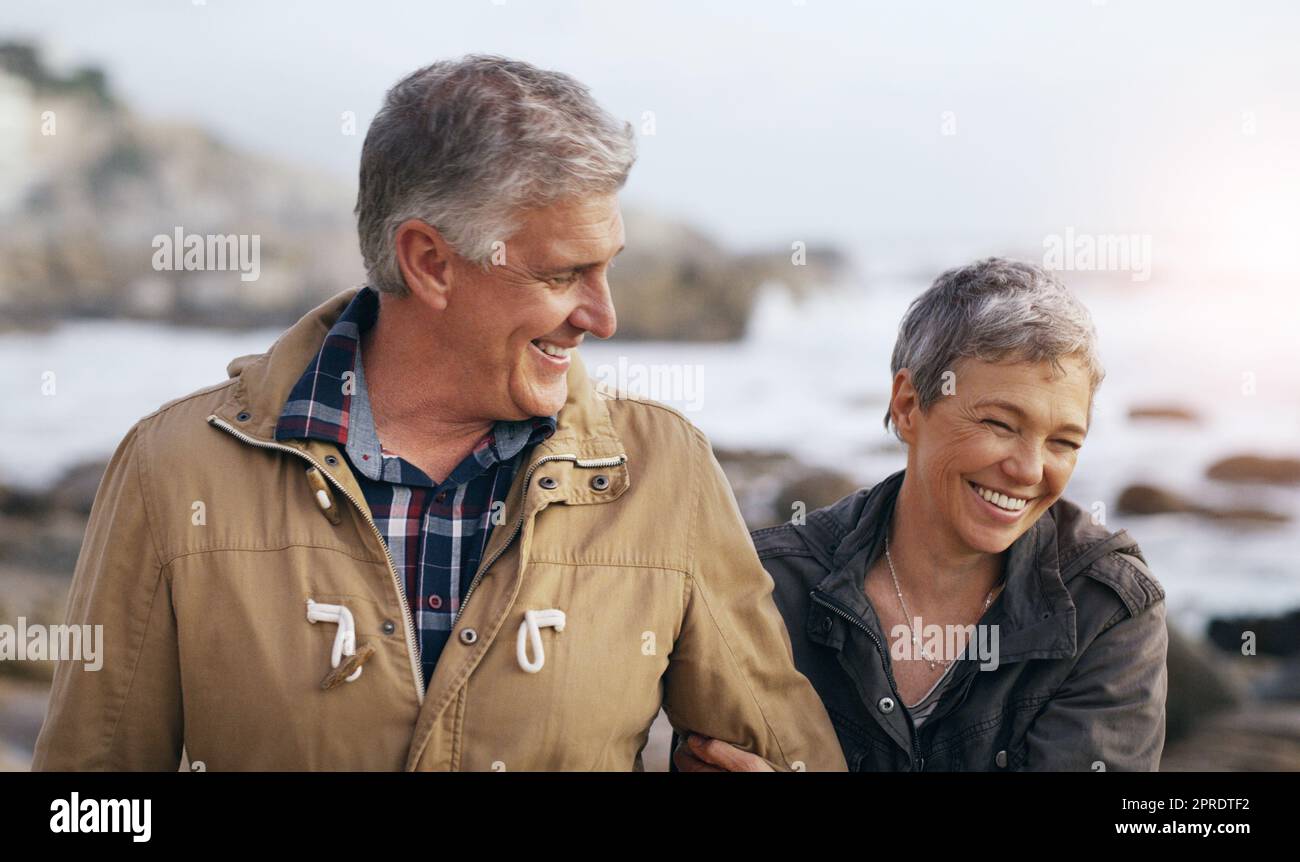 Tout comme les bons vieux jours. Un beau couple de personnes âgées qui fait une promenade à la plage. Banque D'Images