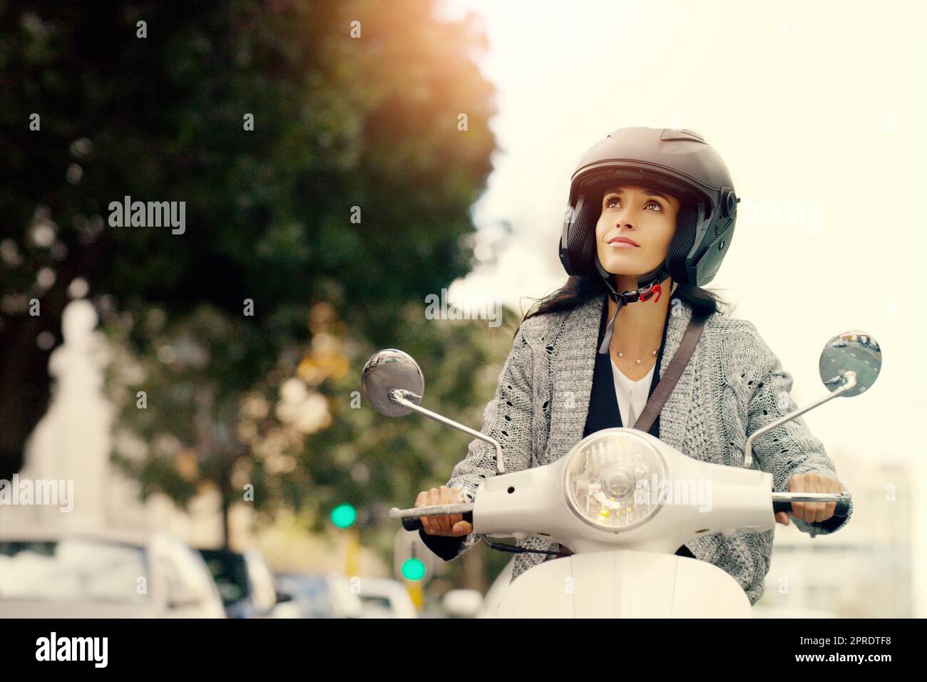 Toujours viser haut et avoir des espoirs encore plus élevés. Une jeune femme attirante à conduire son scooter à travers la ville. Banque D'Images