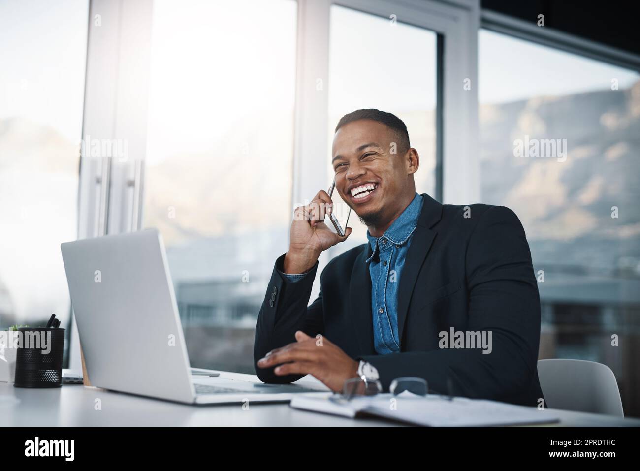 Vous pouvez lui faire confiance pour garder vos affaires entre des mains sûres. Un beau jeune homme d'affaires parlant sur un téléphone portable tout en travaillant dans un bureau. Banque D'Images