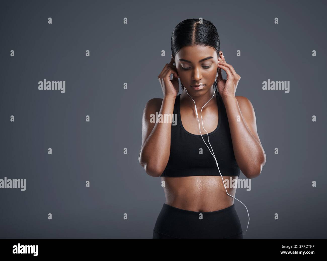 Choisissez de la musique pour vous mettre dans l'état d'esprit approprié. Photo studio d'une jeune femme sportive écoutant de la musique sur fond gris. Banque D'Images