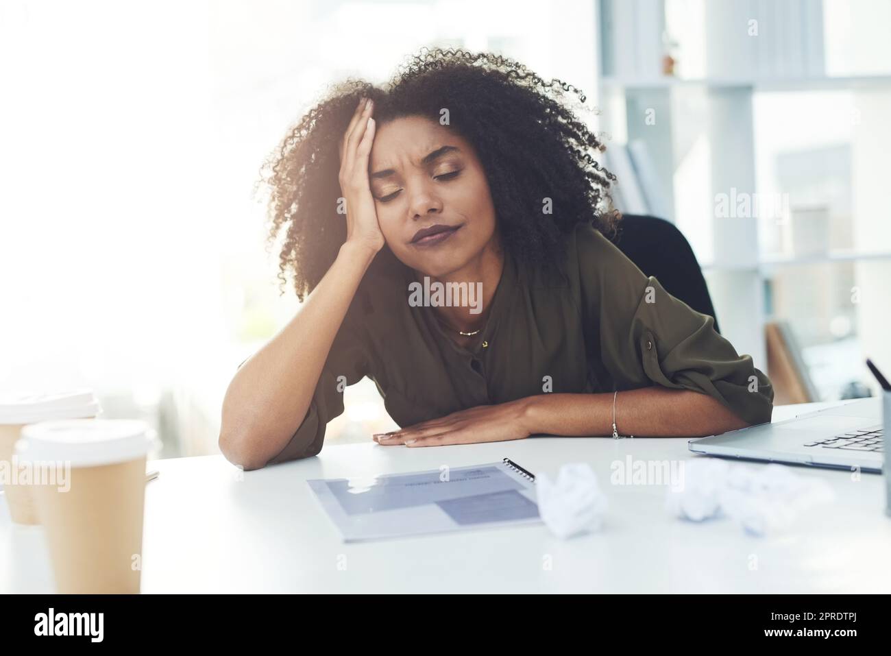 Accrochez-vous là, le désespoir engendre toujours des idées brillantes : une jeune femme d'affaires assise à son bureau qui a l'air fatiguée et stressée. Banque D'Images