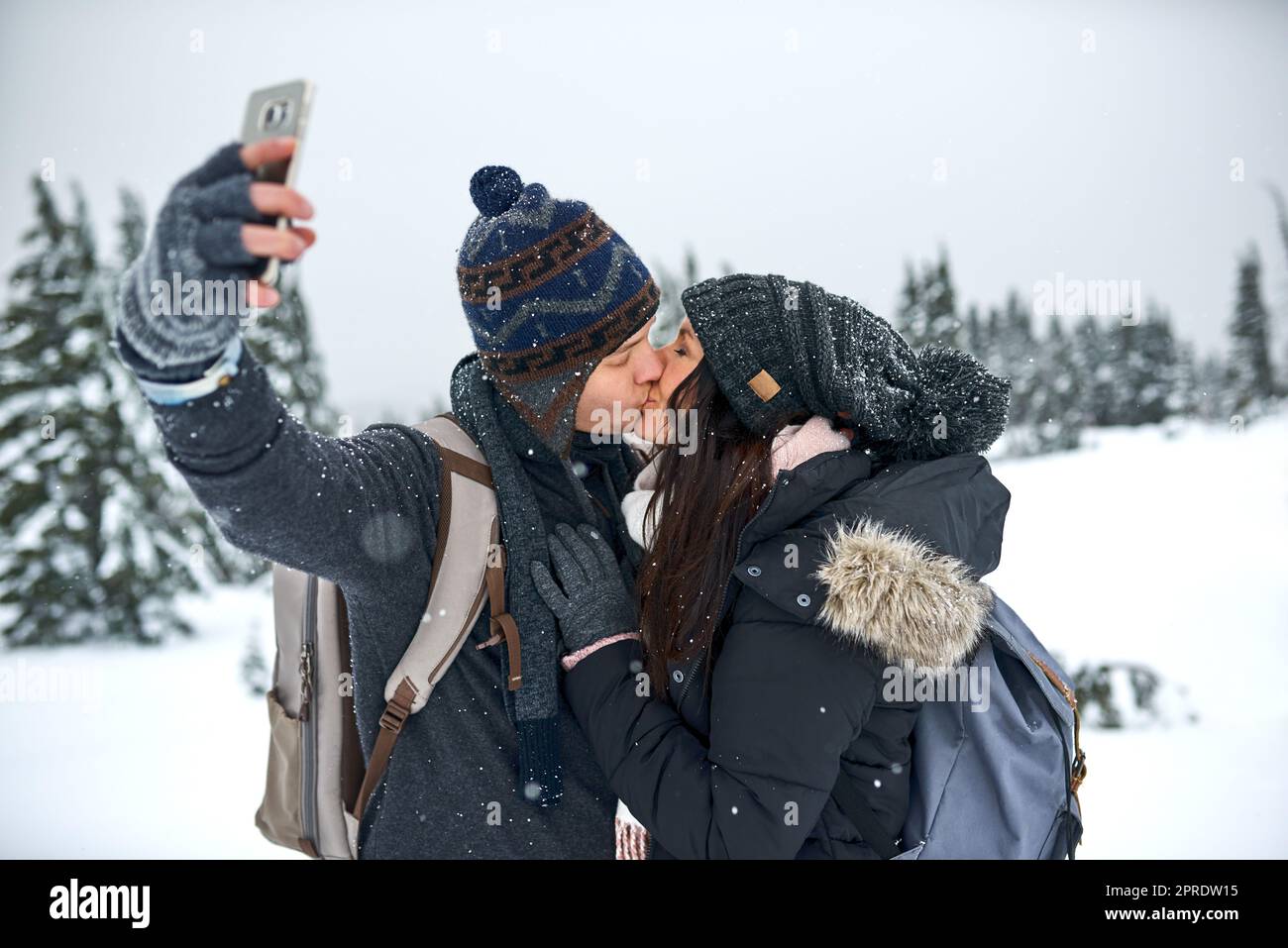 Embrassez-moi avant que vos lèvres ne gèlent. Un homme prenant un selfie avec sa petite amie alors qu'il était sur la neige. Banque D'Images