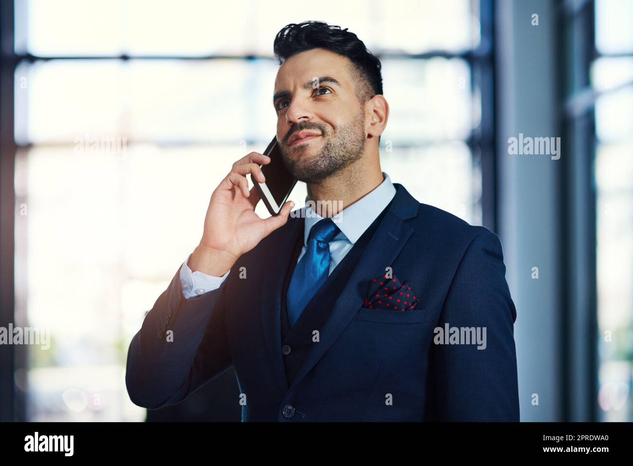 Quand l'occasion se présente, c'est celui de savoir en premier. Un jeune homme d'affaires parlant sur un téléphone portable dans un bureau. Banque D'Images