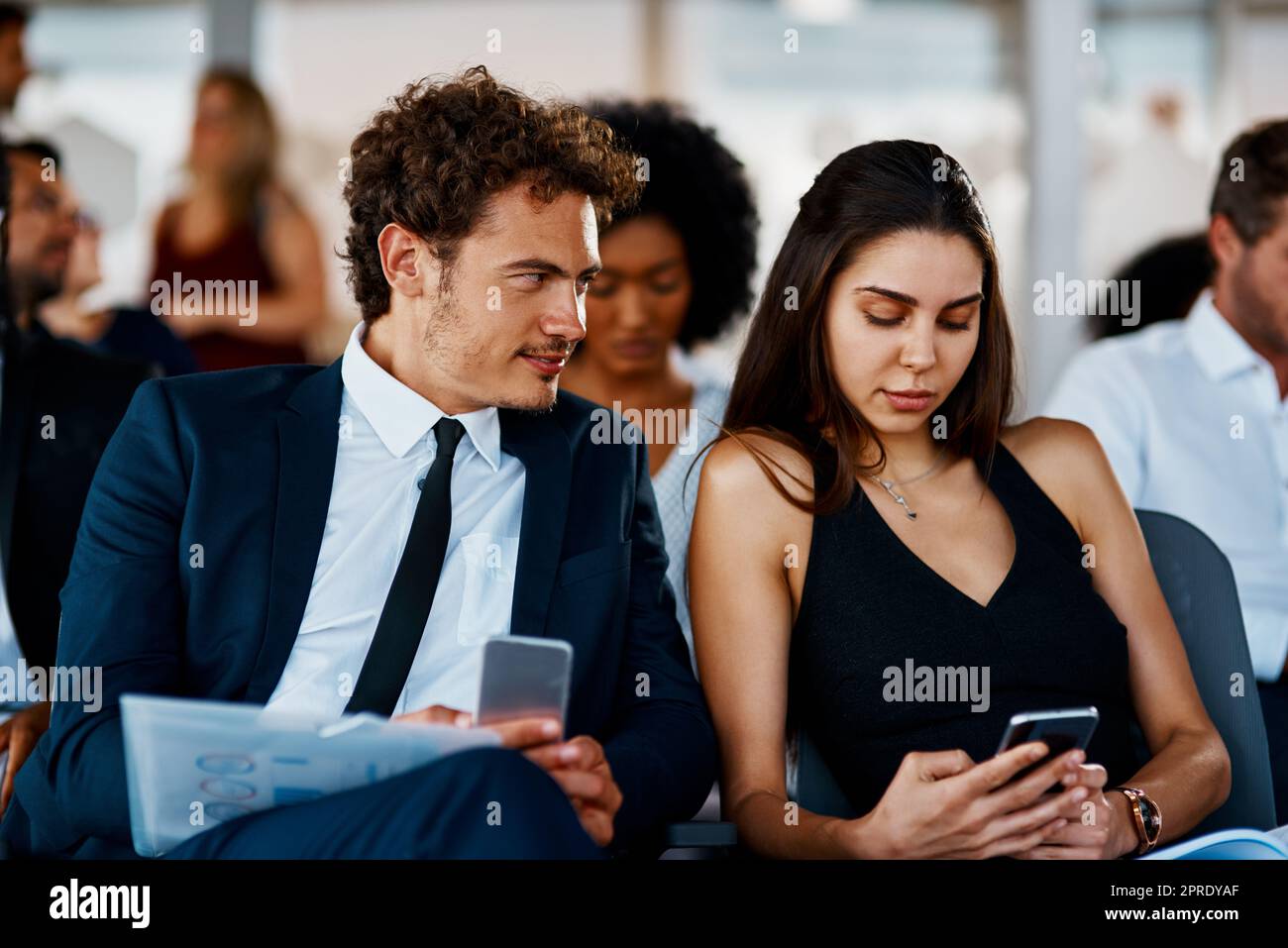 Profitez de chaque occasion d'apprendre. Deux jeunes hommes d'affaires utilisant leur téléphone portable lors d'un séminaire dans la salle de conférence. Banque D'Images