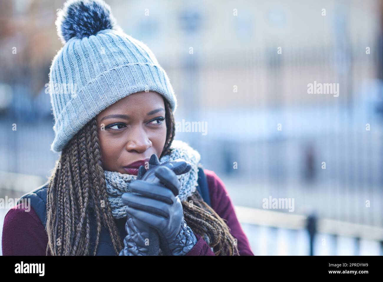 Une jeune femme qui a l'air attentionnés lors d'une journée d'hiver en plein air, elle a été garnie de chaleur lorsque la température baisse. Banque D'Images