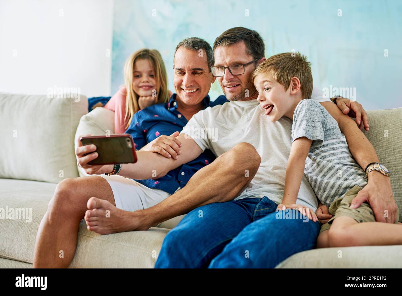 Un plaisir pour toute la famille. Une famille affectueuse de quatre personnes prenant des selfies sur le canapé à la maison. Banque D'Images
