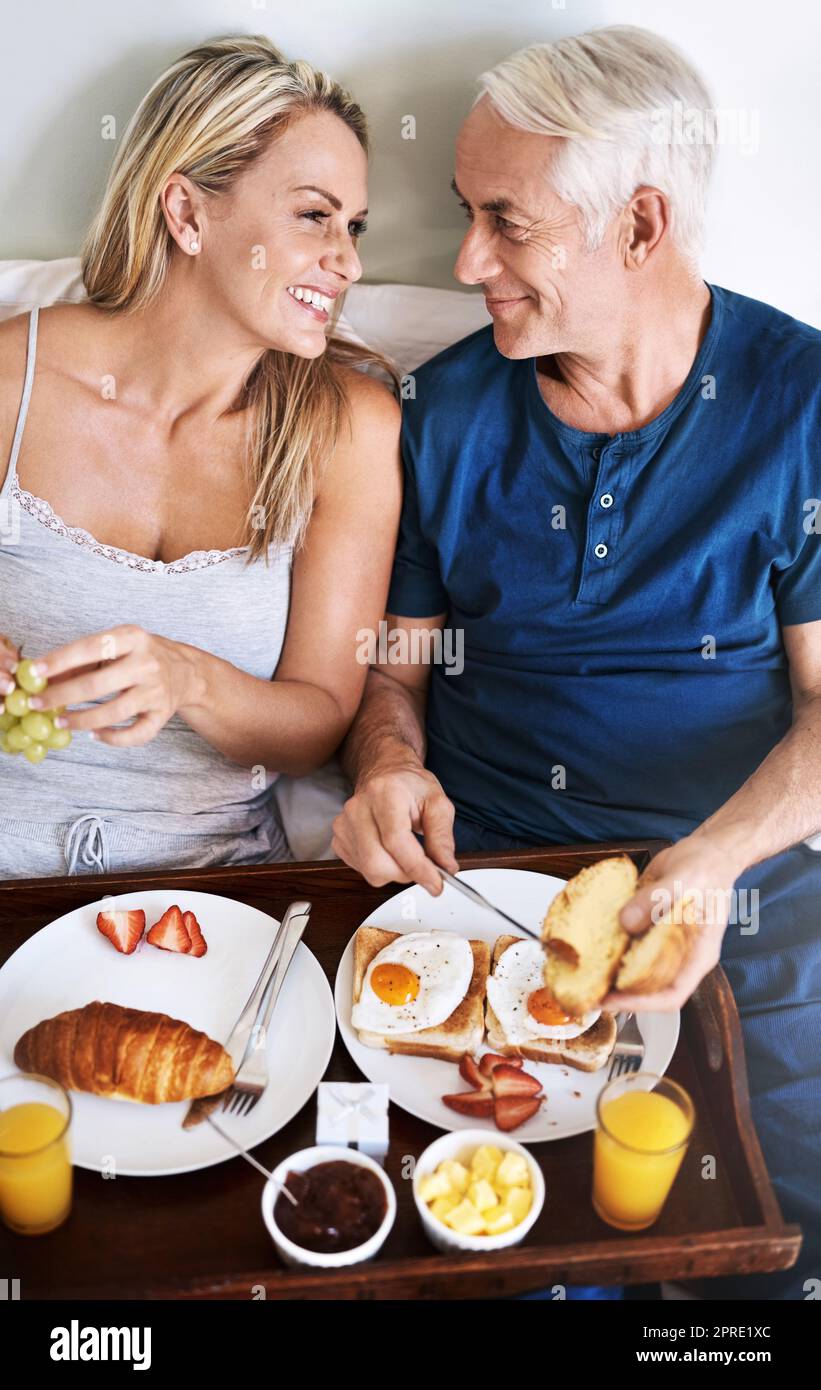 Je ne peux pas imaginer un meilleur début de journée. Un couple affectueux et mature qui prend son petit déjeuner au lit à la maison. Banque D'Images