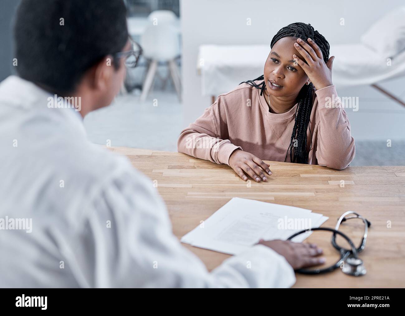 Patient malade, malade ou stressé avec un médecin qui parle en consultation médicale, en contrôle ou en visite dans une clinique, un hôpital ou un centre de soins de santé. Femme fatiguée avec mal de tête expliquant les symptômes à la gp professionnelle Banque D'Images