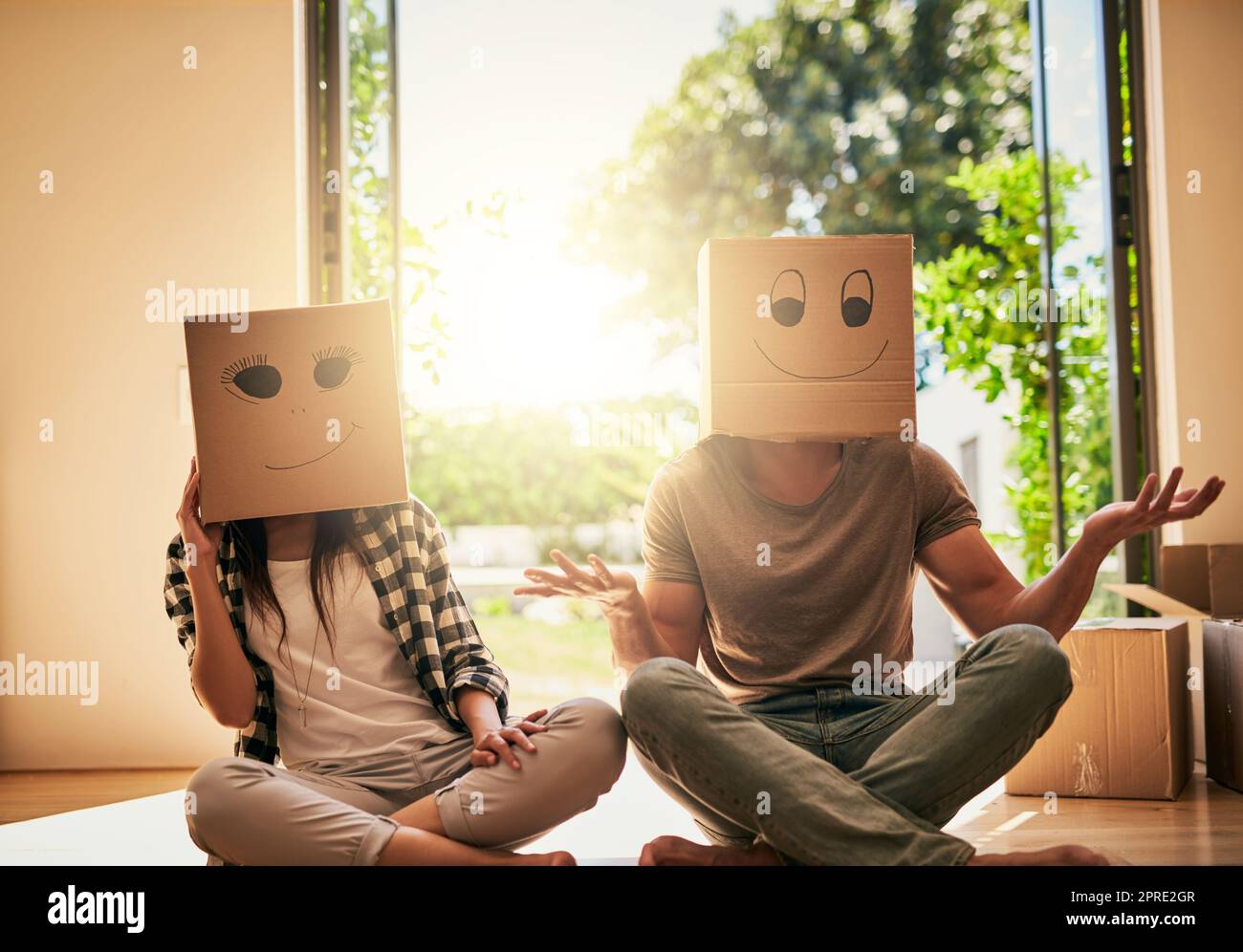 Un couple qui porte des boîtes avec des smiley visages dessinés sur la tête. Banque D'Images