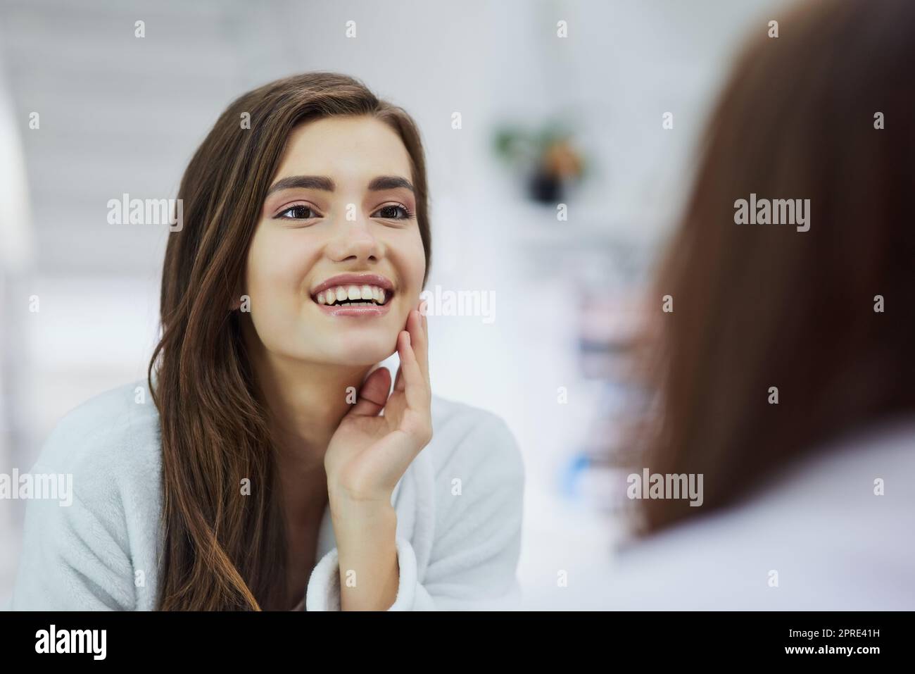 Oui, c'est vrai, IM parfait. Une jeune femme attrayante regardant dans un miroir avec sa main touchant sa joue à la maison pendant la journée. Banque D'Images