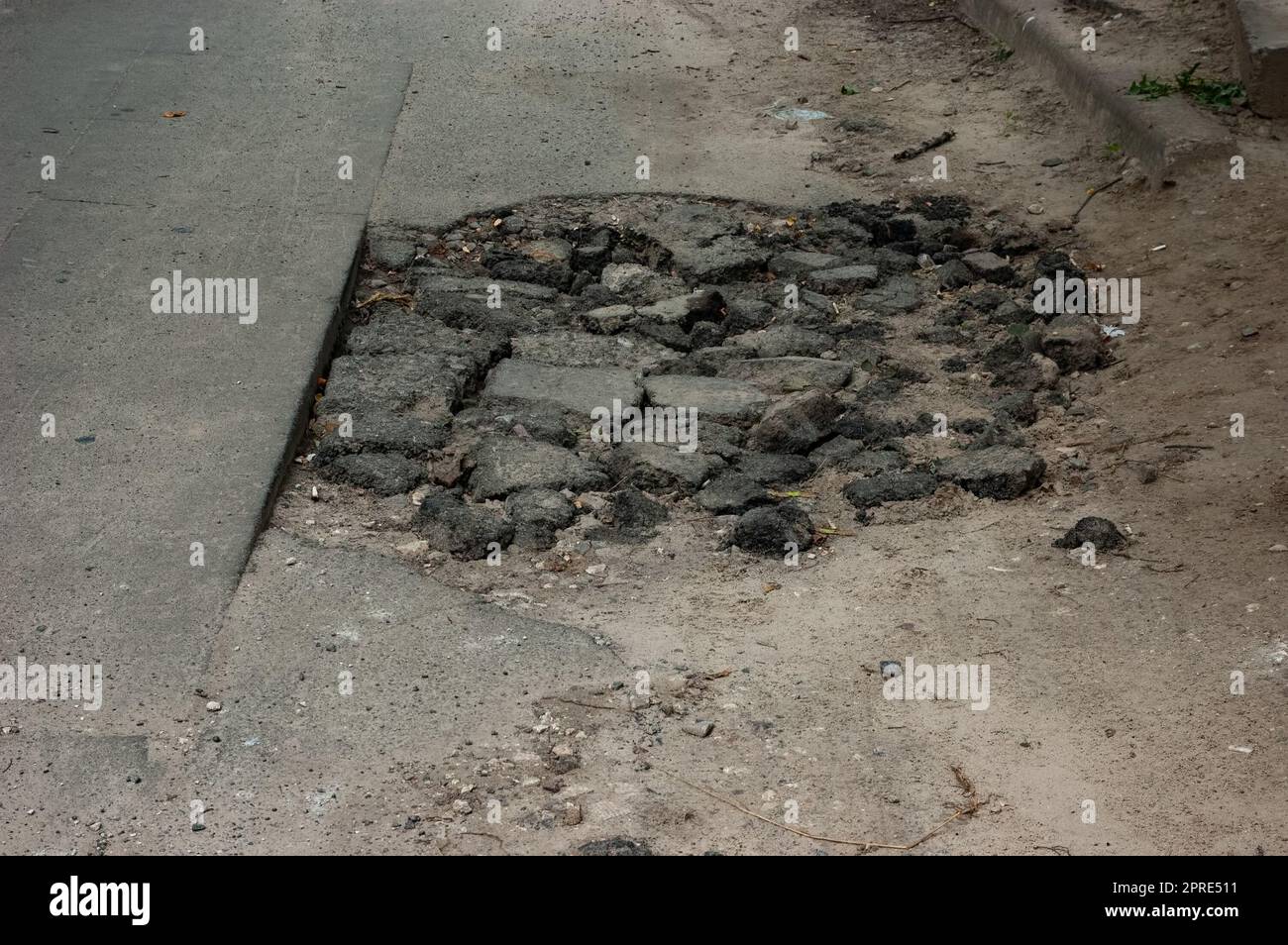 Un trou dans l'asphalte avec des morceaux d'asphalte cassés Banque D'Images