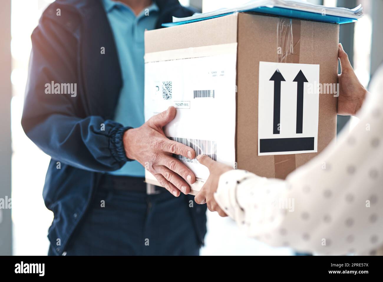 Livré à temps à votre domicile. Un liveur méconnaissable qui distribue un colis à une cliente. Banque D'Images