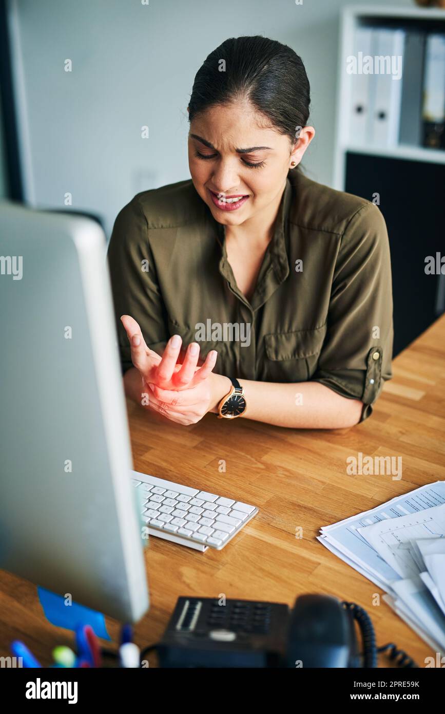 Comment ma main a-t-elle soudainement pris de la force : une jeune femme d'affaires souffrant de douleur dans la main tout en travaillant dans un bureau. Banque D'Images