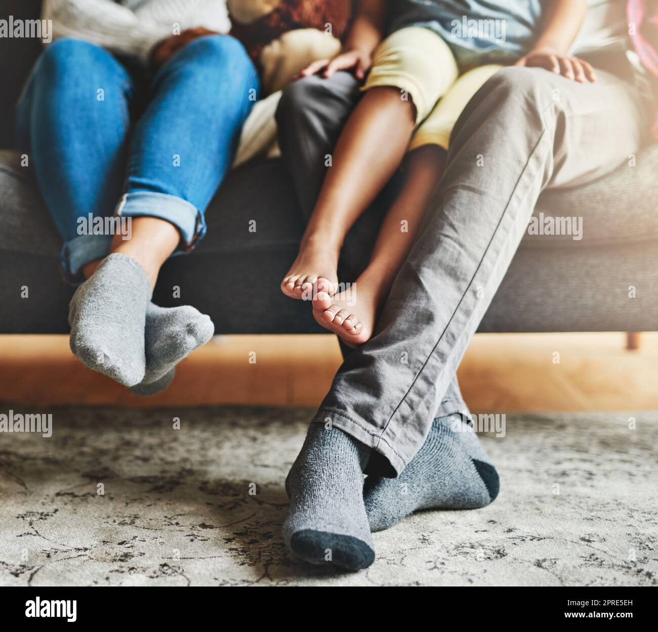 Une famille de trois personnes se détendant ensemble sur le canapé à la maison. Banque D'Images